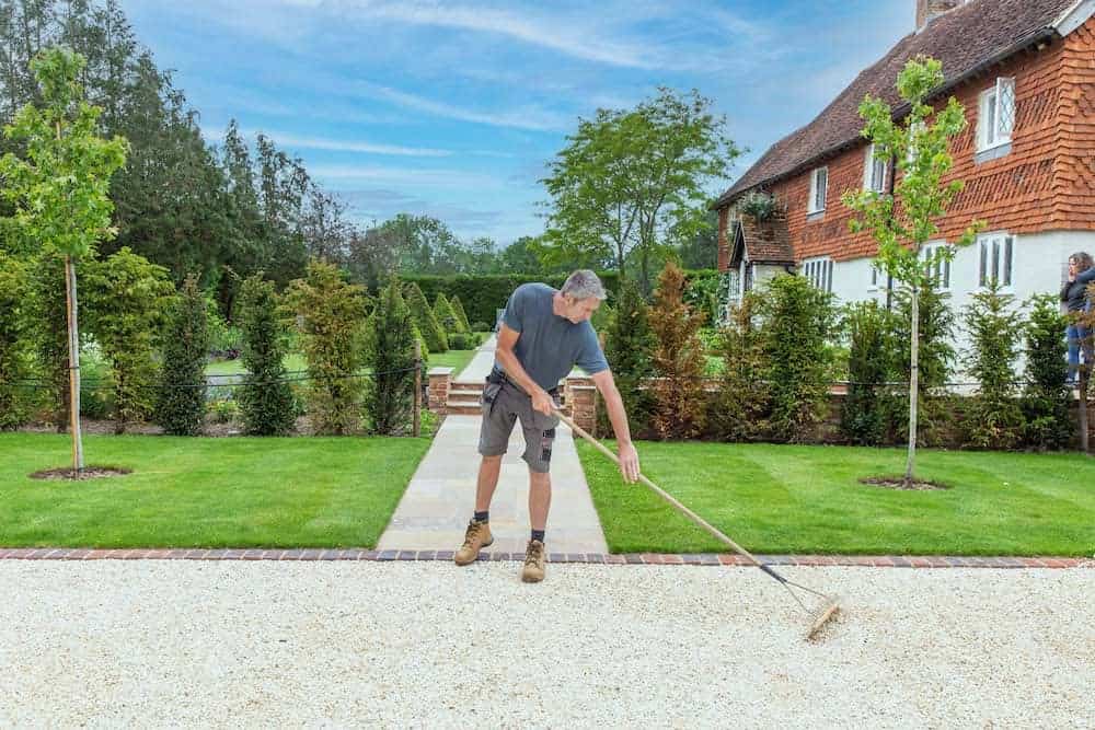 landscape contractors surrey and west sussex showing man raking gravel path